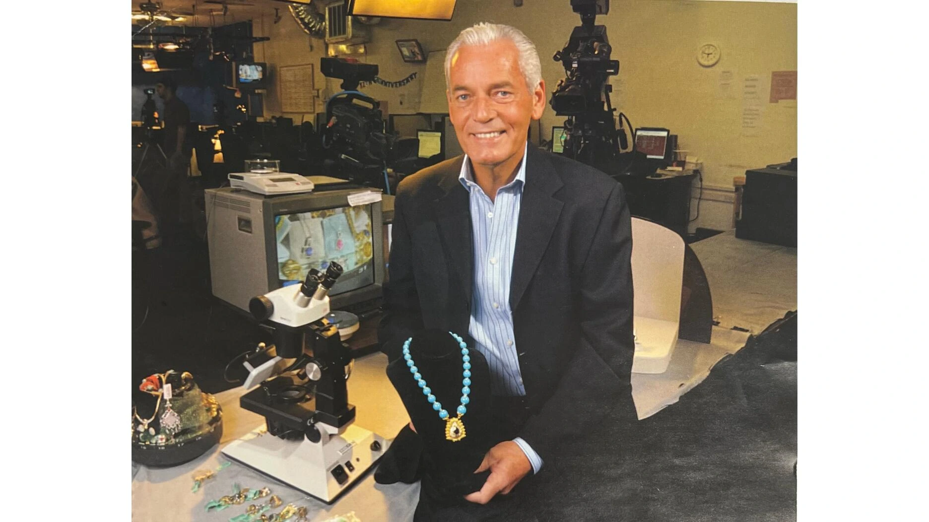 Frank M. Circelli seated in a jewelry studio, smiling in front of gem equipment and displays
