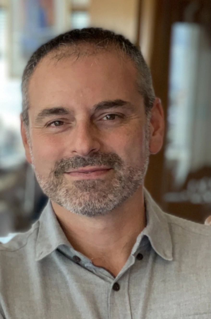 Portrait photo of Fabien Frankel smiling indoors in a casual shirt